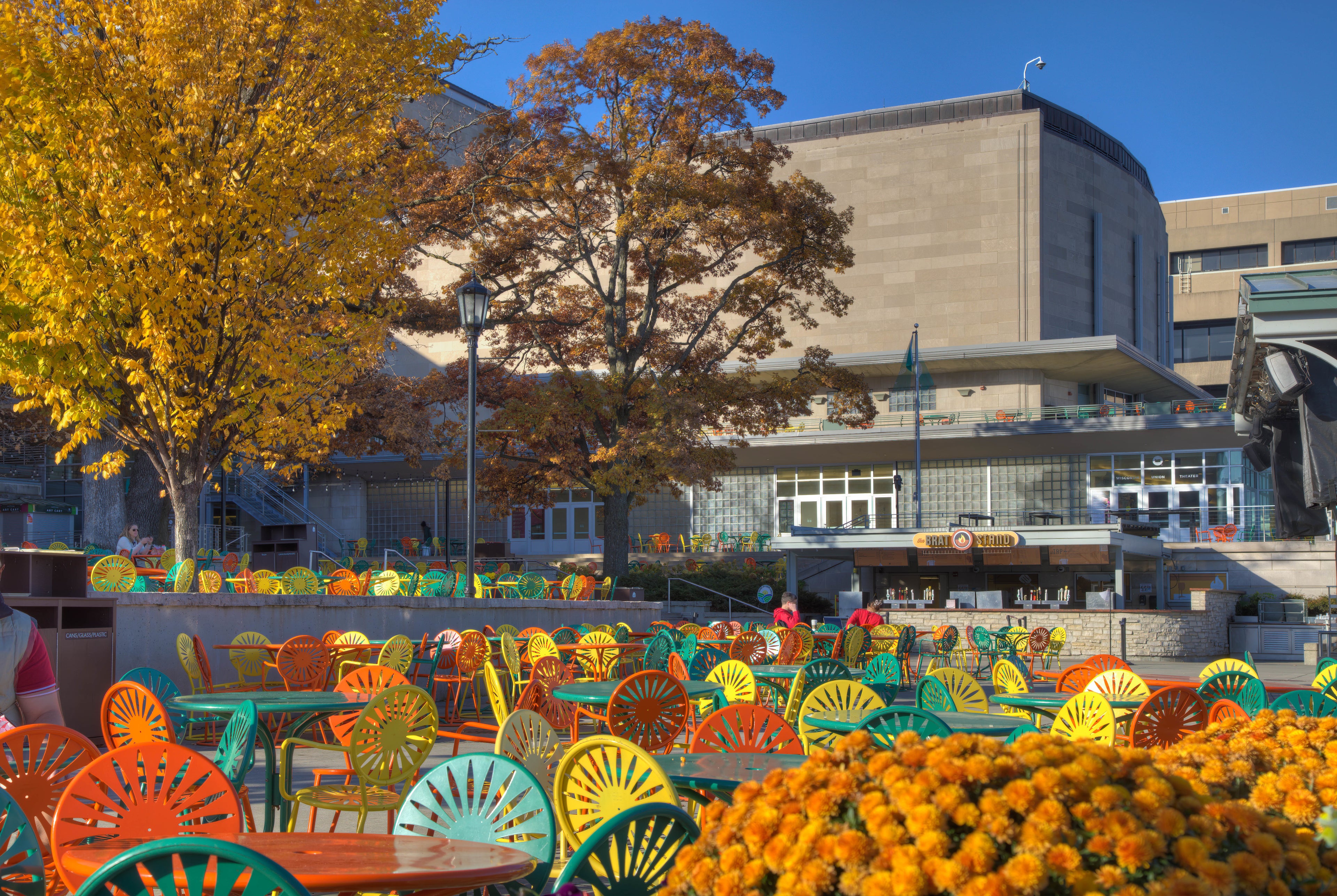Tables at the Memorial Union Terrace with fall foliage on display.